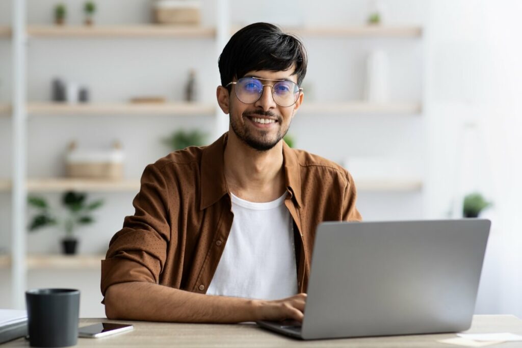 man smiling and working on laptop