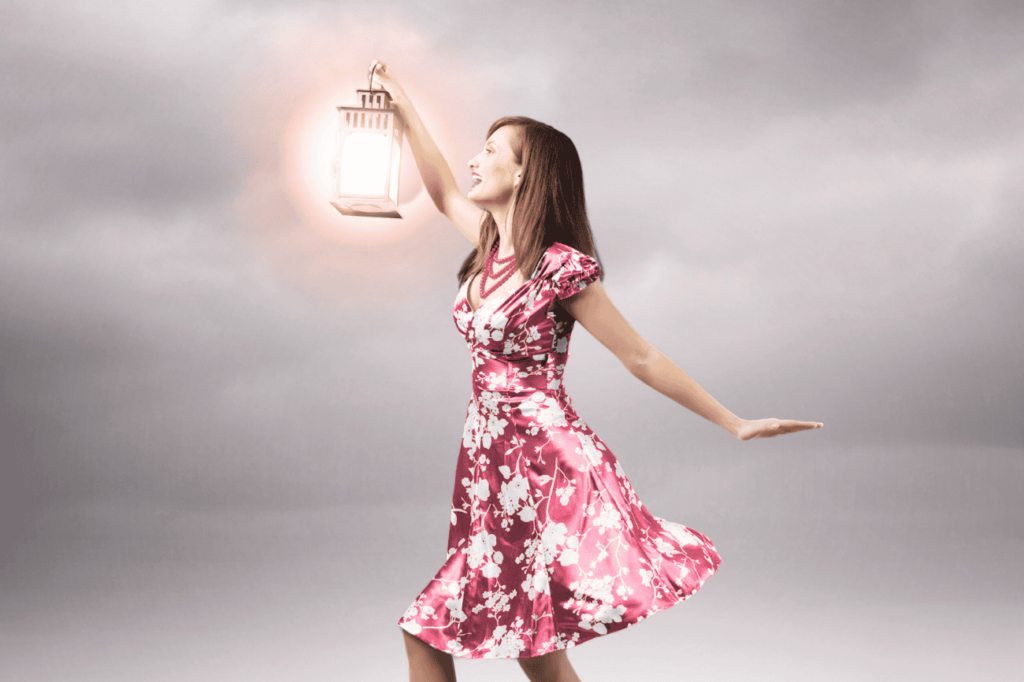 woman in pink dress holding a lantern searching on a gray cloudy day